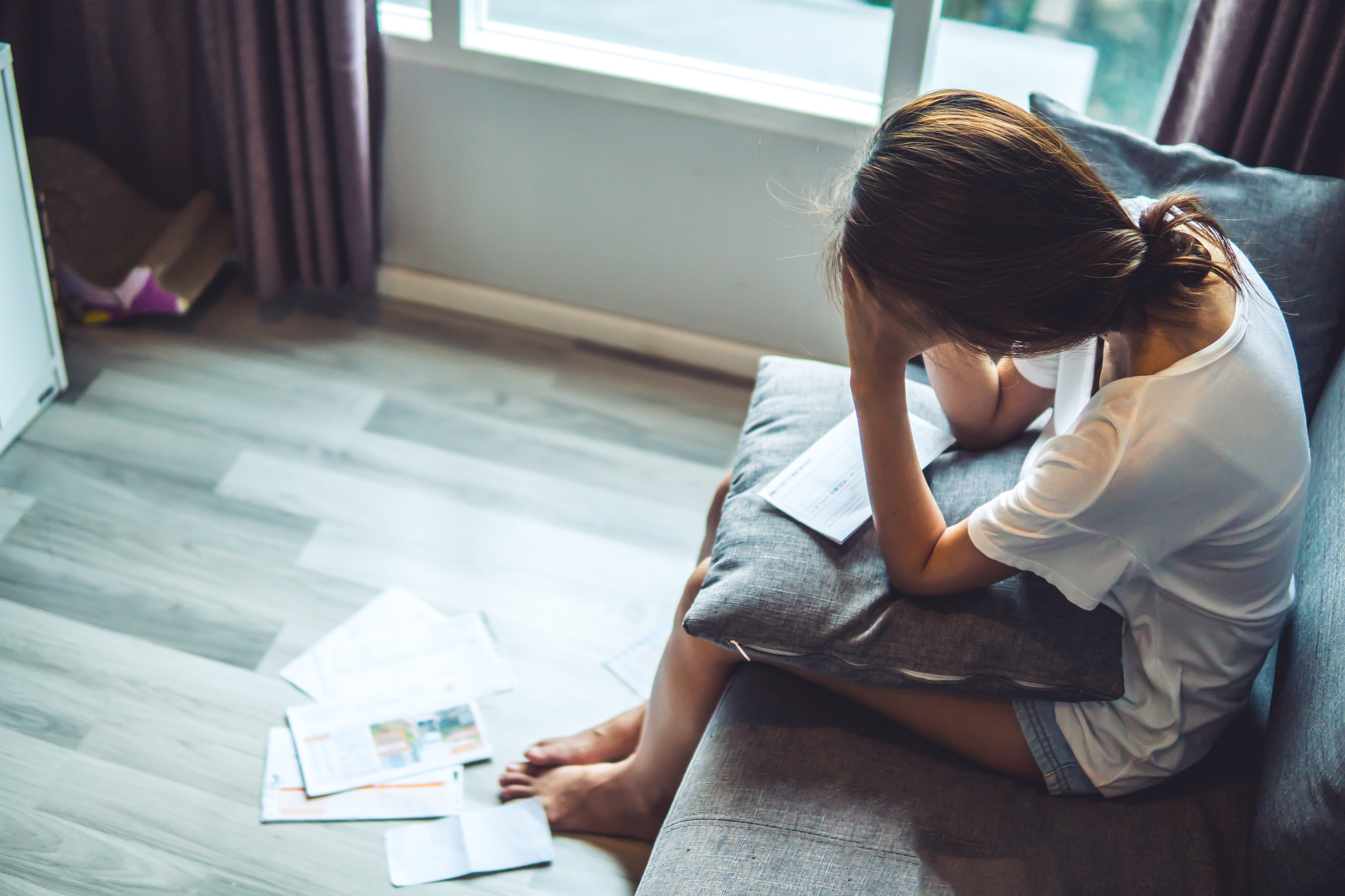 woman looking at stack of bills in her lap